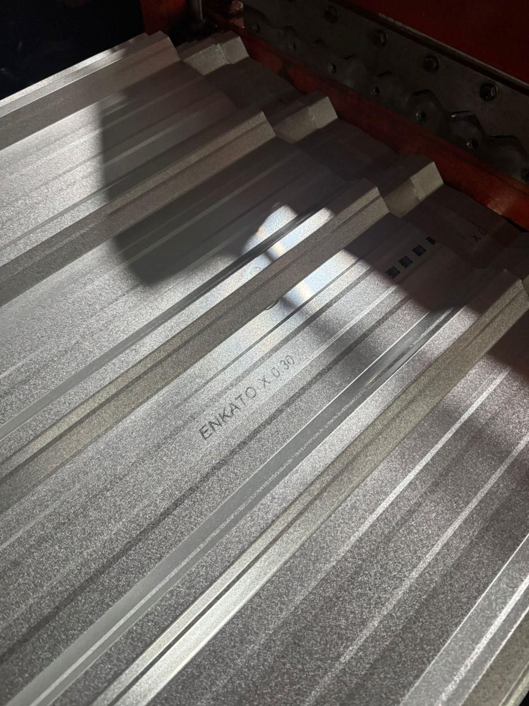 Tulisan emboss ENKATO X 0.30 pada lembaran spandek